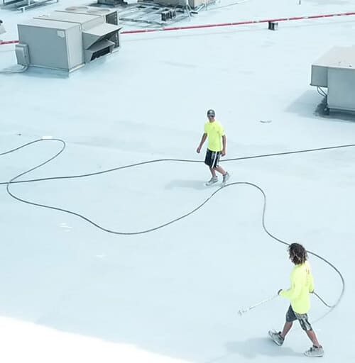 Contractors apply roof restoration coating.