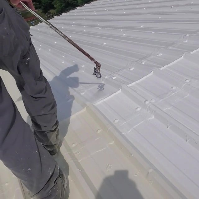 Roofer applies elastomeric coating.
