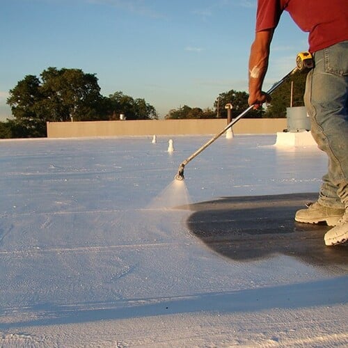 Roofer applies commercial roof coating.