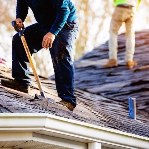 Residential roofer tears out shingles.