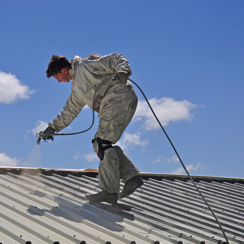 worker coating a metal roof