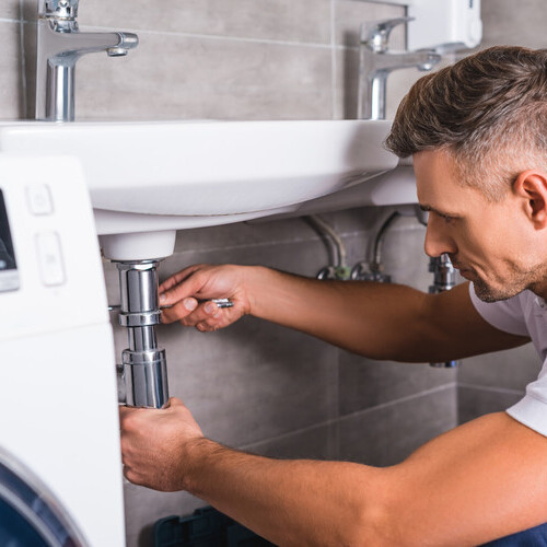 adult plumber fixing sink at bathroom