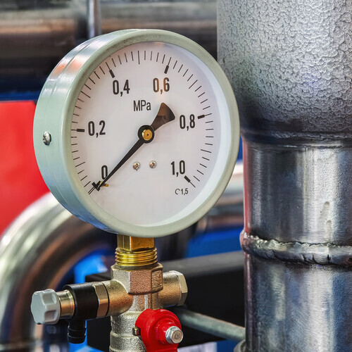 A pressure gauge displays measurements in MPa next to a metallic pipeline in an industrial setting. The setup highlights important safety and operational indicators.