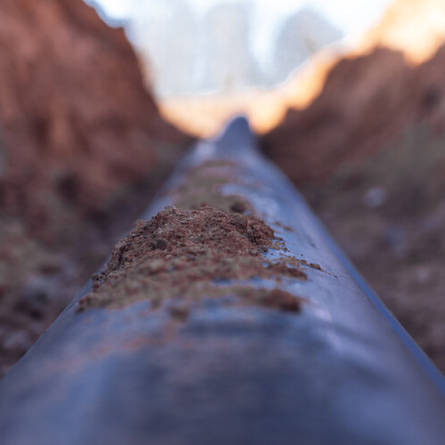 Plastic water pipe is in the trench in the direction under a blue sky residential buildings Close up
