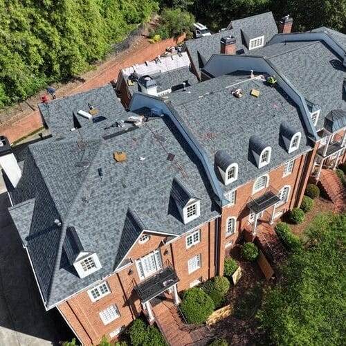 Residential roofer works on shingle roof.