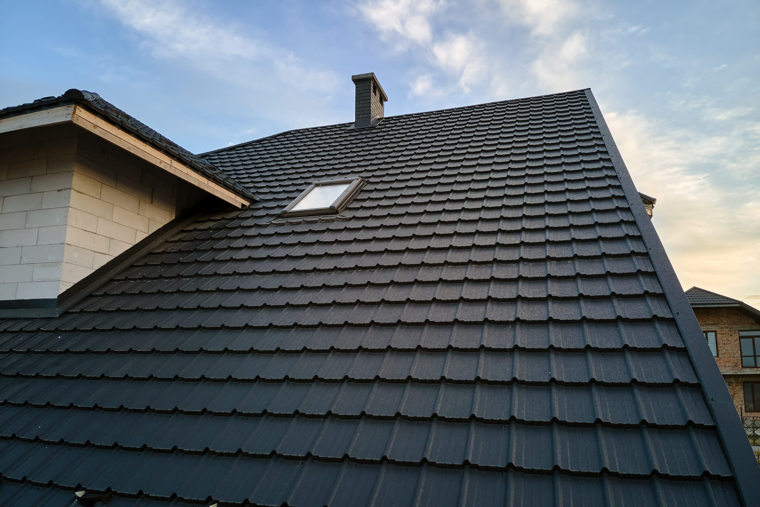 Closeup of house roof top covered with metallic shingles.Tiled covering of building