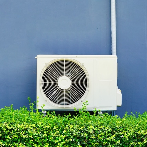 hvac against a blue wall and bush outdoors
