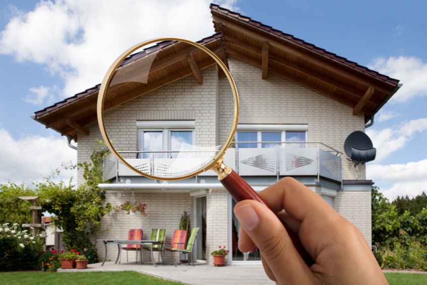 magnifying glass in front of a house signifying a roof inspection