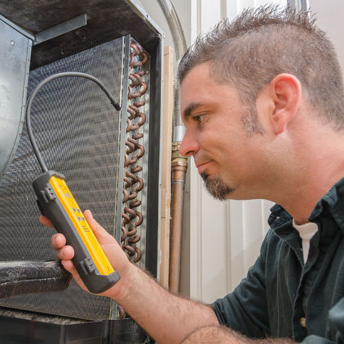 HVAC technician working with tools to correct HVAC issue