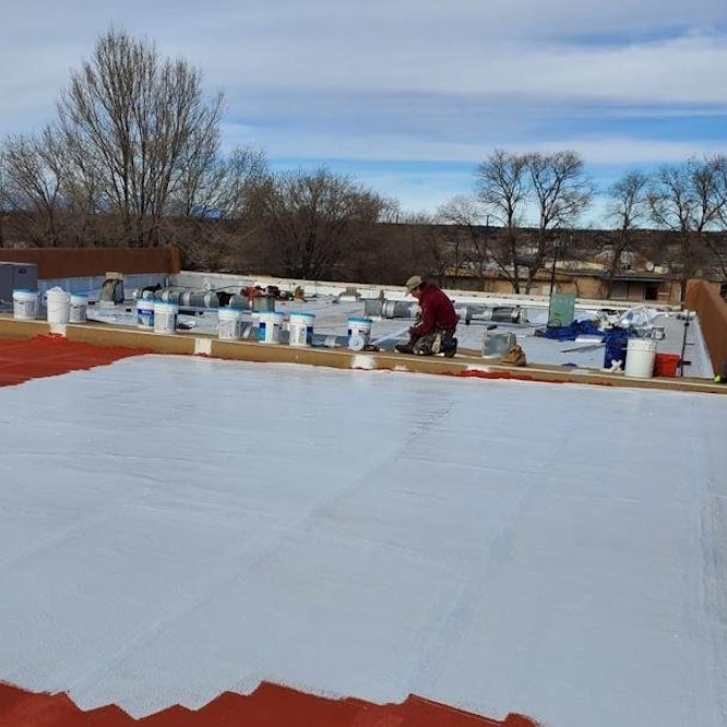 Flat roof coating procedure photographed in process.