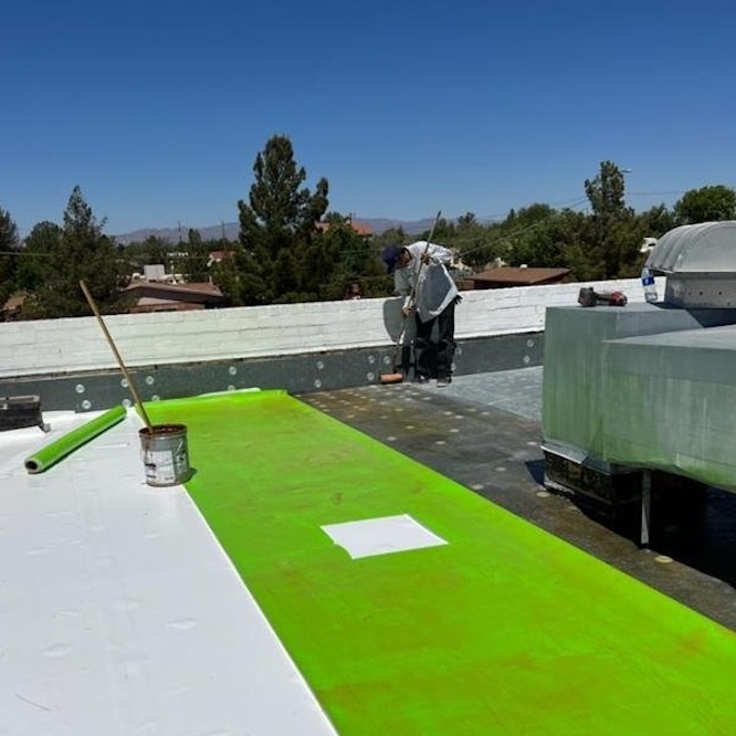 Technician apply metal roof coating.