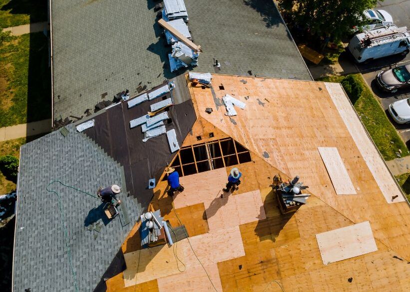 A roof is being replaced by numerous roofers working together.